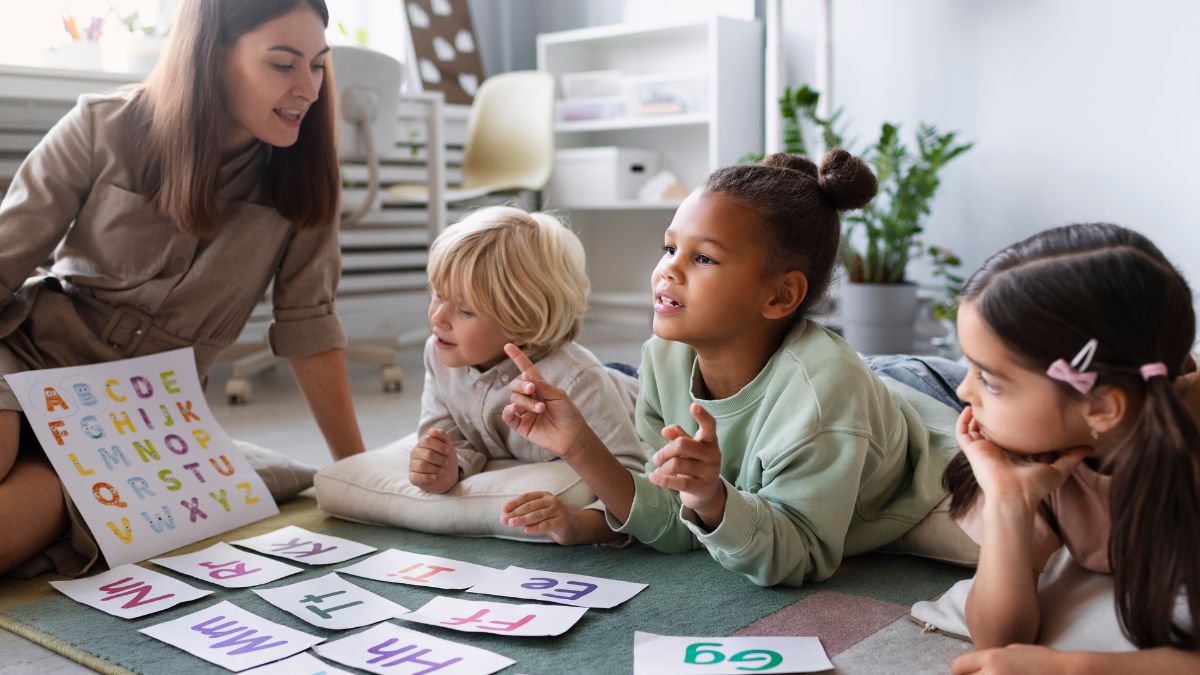 Activities for autism classroom, a female instructor shows a picture book to children sitting on the floor with play activity pieces around them.