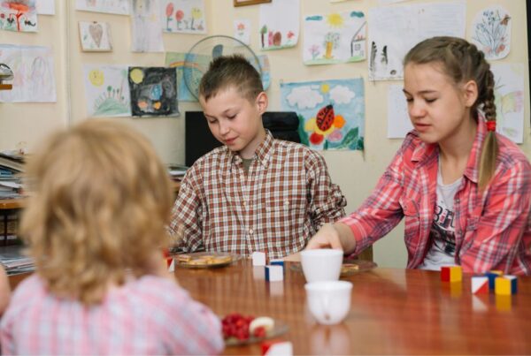 Activities for autism classroom, older children sit around a table with puzzles and toy pieces in front of them during a classroom activity.