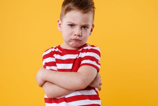 A boy frowns at the camera against a yellow background, illustrating the stigma around autism.