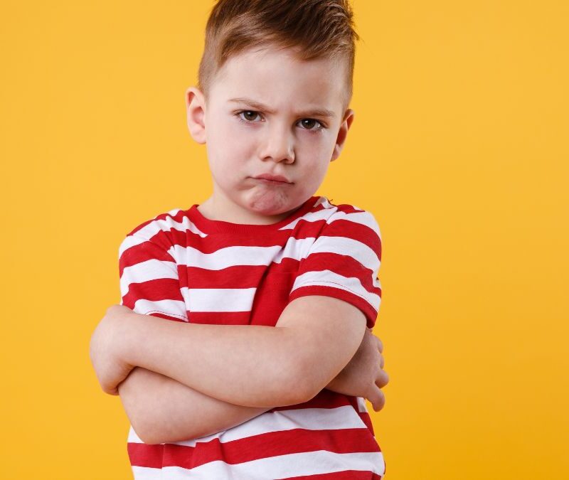 A boy frowns at the camera against a yellow background, illustrating the stigma around autism.