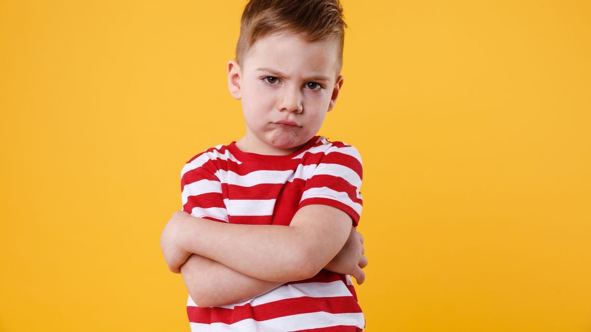 A boy frowns at the camera against a yellow background, illustrating the stigma around autism.