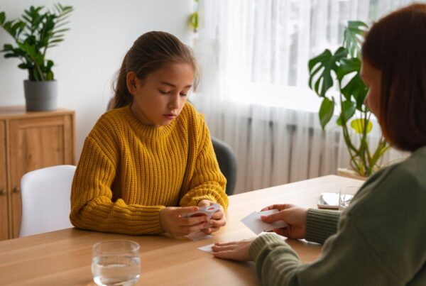 A young girl with her eyes downcast speaks to a concerned counselor, reflecting the stigma surrounding autism.