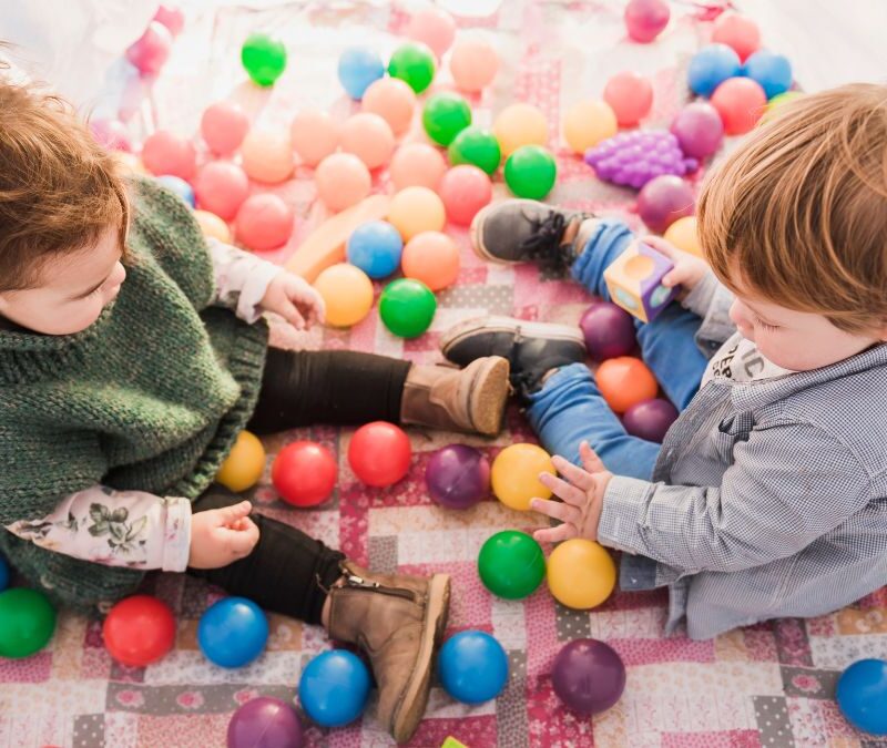 Sensory items autism, two children play with circular sensory toys on the floor, captured from a top-view angle.