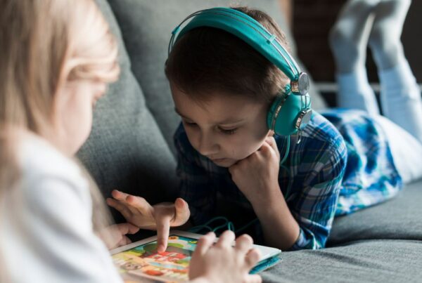A young boy relaxes on a sofa, fully engaged in a puzzle game while listening on headphones, illustrating autism repetitive behavior.