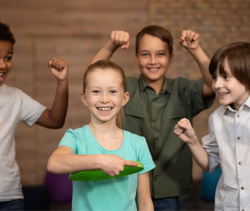 A young girl stands confidently at the center of a group, looking at the camera with a focused expression, demonstrating leadership skills.