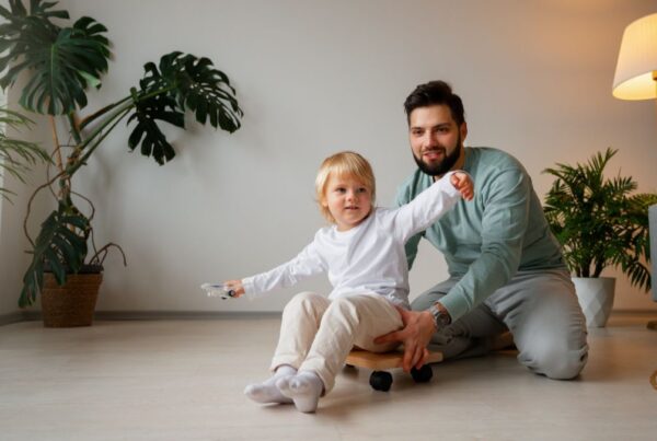 A father guides his son through a movement activity at home as part of ABA therapy.
