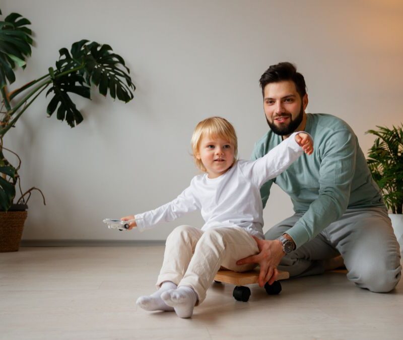A father guides his son through a movement activity at home as part of ABA therapy.