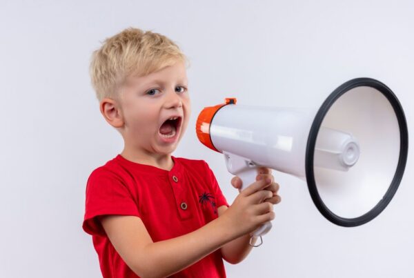 Echolalia autism, a child wearing a red shirt speaking through a megaphone.
